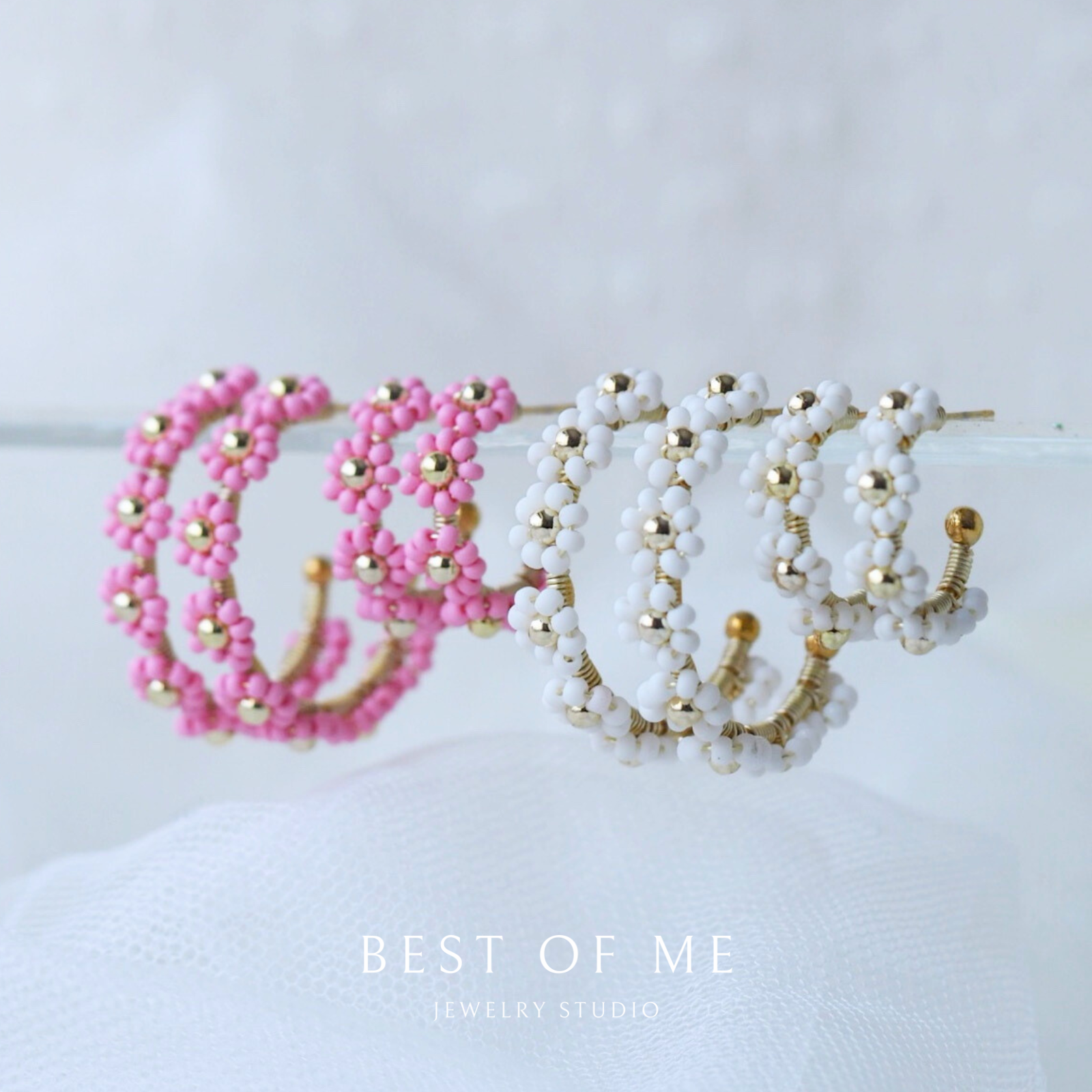 Two beaded headbands, one pink and one white with gold accents, on a white surface.