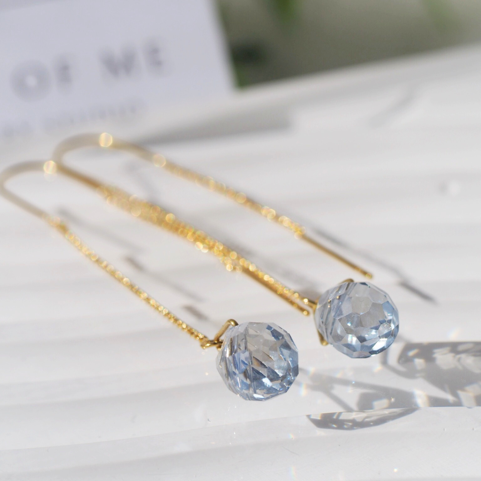 Gold earrings with blue gemstones on a light background