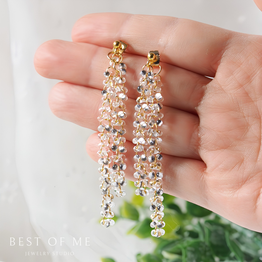 Hand holding a pair of elegant  beaded earrings with a blurred background