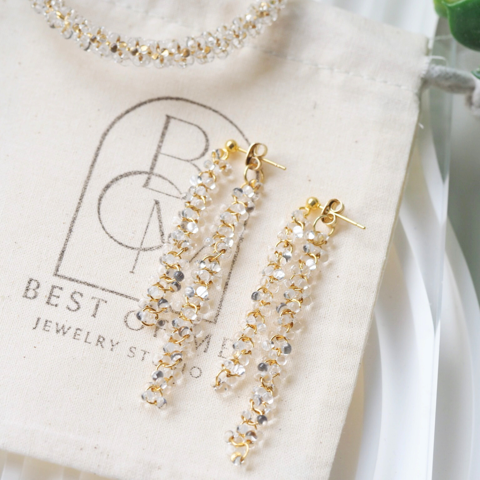 delicate clear glass beaded earrings on a jewelry pouch with 'Best of Me' branding jewelry pouch.