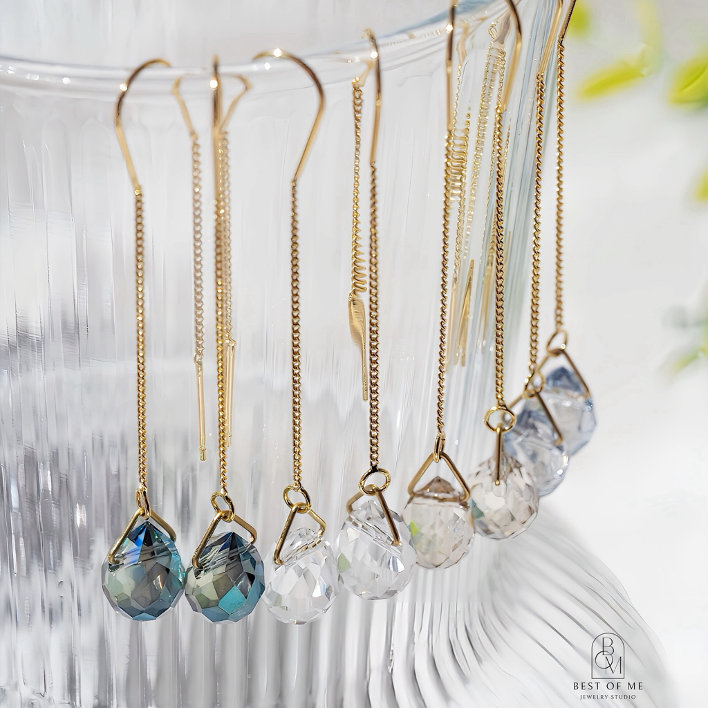 Gold earrings with crystal glass beads on a white stand