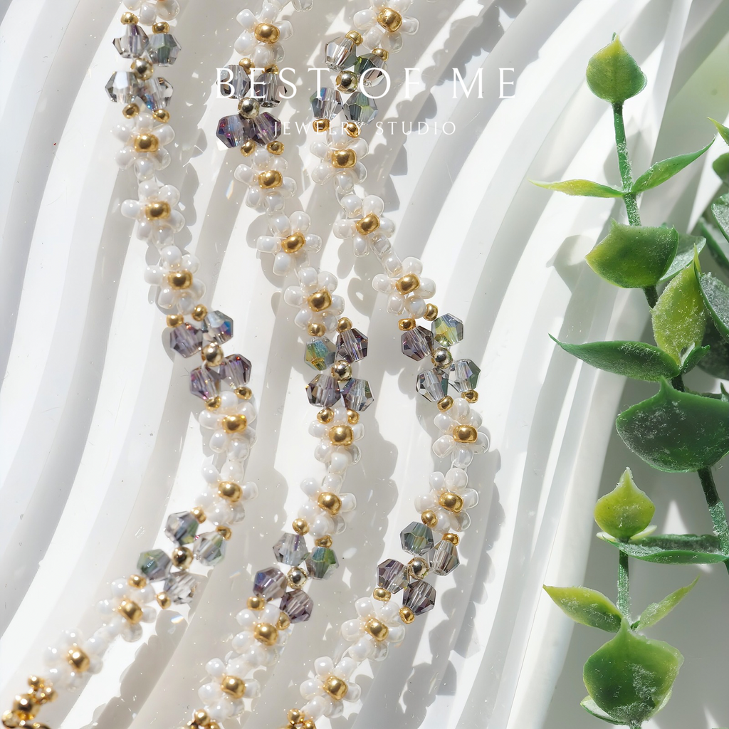 handmade bracelet with beads and crystals on a white background with green leaves.