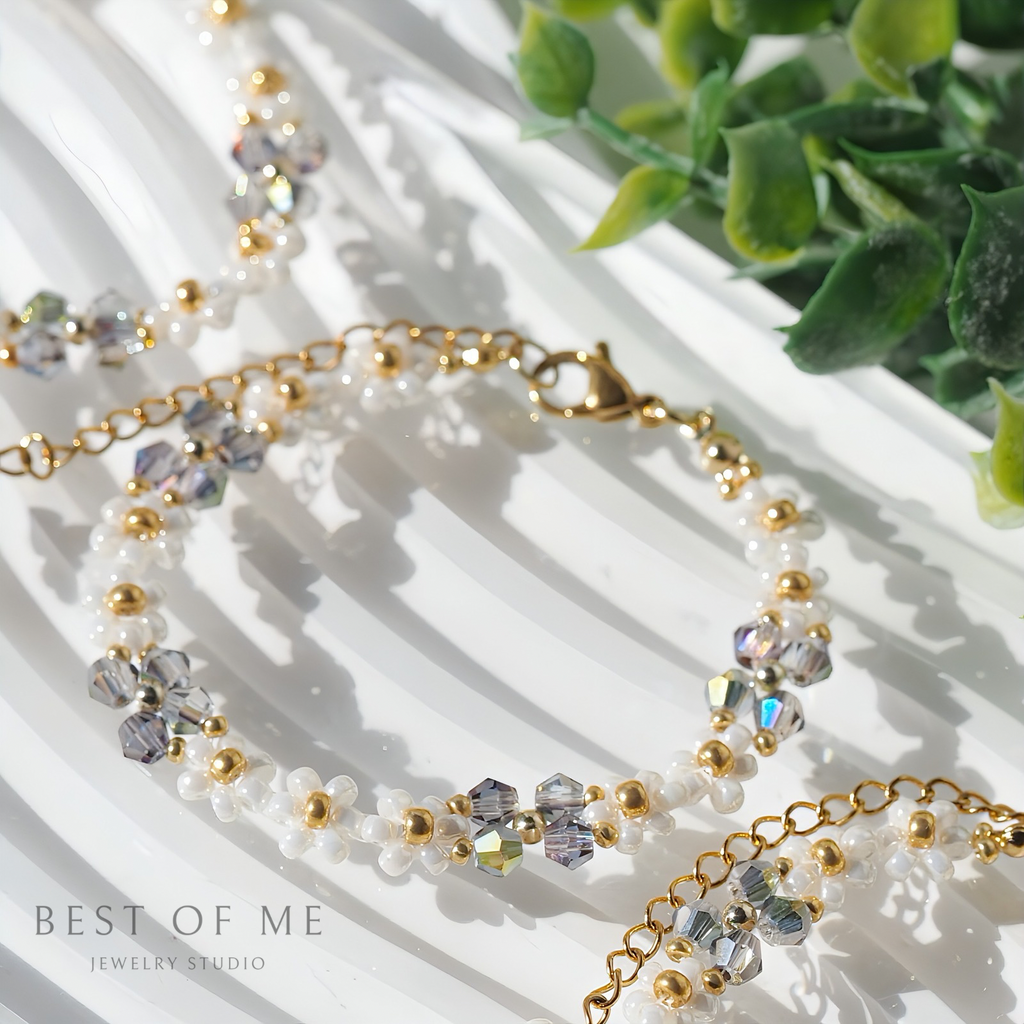 delicate bracelet with beads and crystals on a white surface with greenery