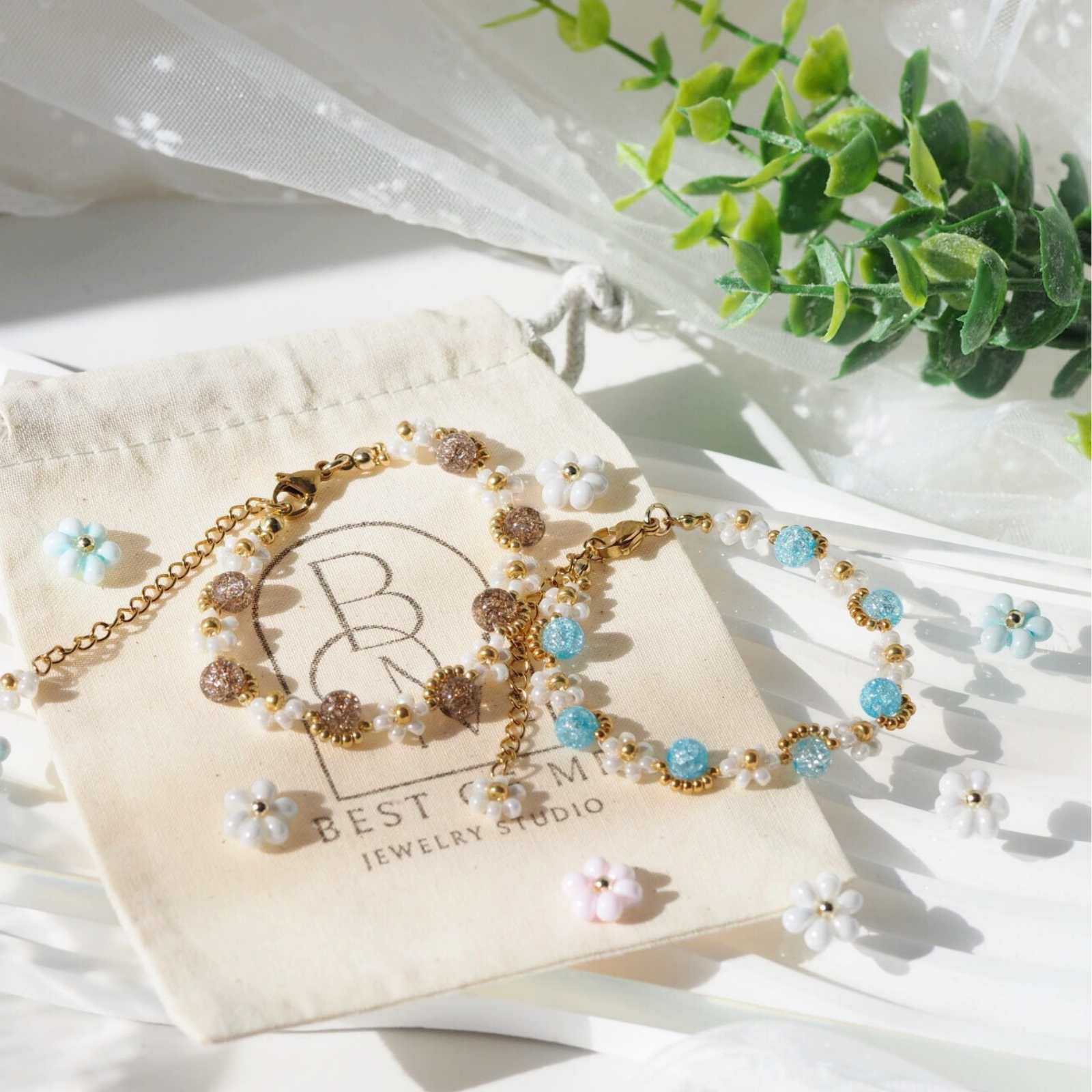 handmade Bracelet with floral design on a Best of Mine Jewelry Studio jewelry bag with greenery in the background